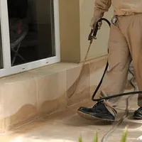 General pest control technician spraying exterior perimeter around a home in Arvada, CO